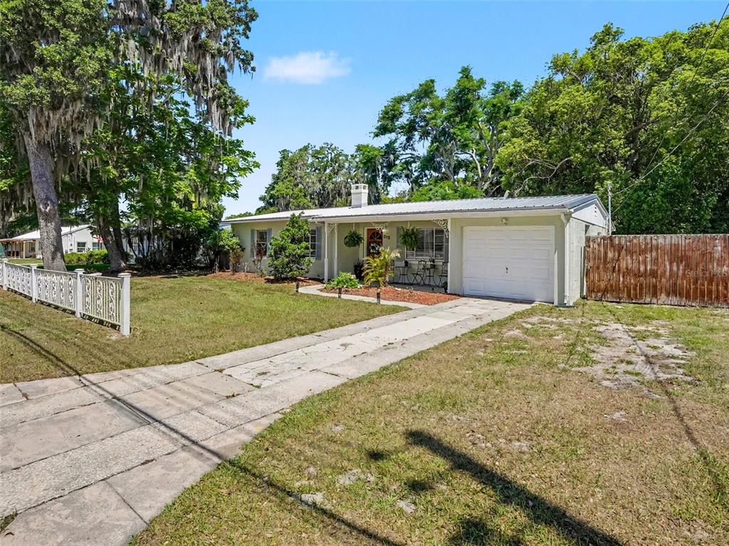 A single-story house with a white garage, a metal roof, and a front lawn — 315 W 11TH AVENUE, MOUNT DORA, FL