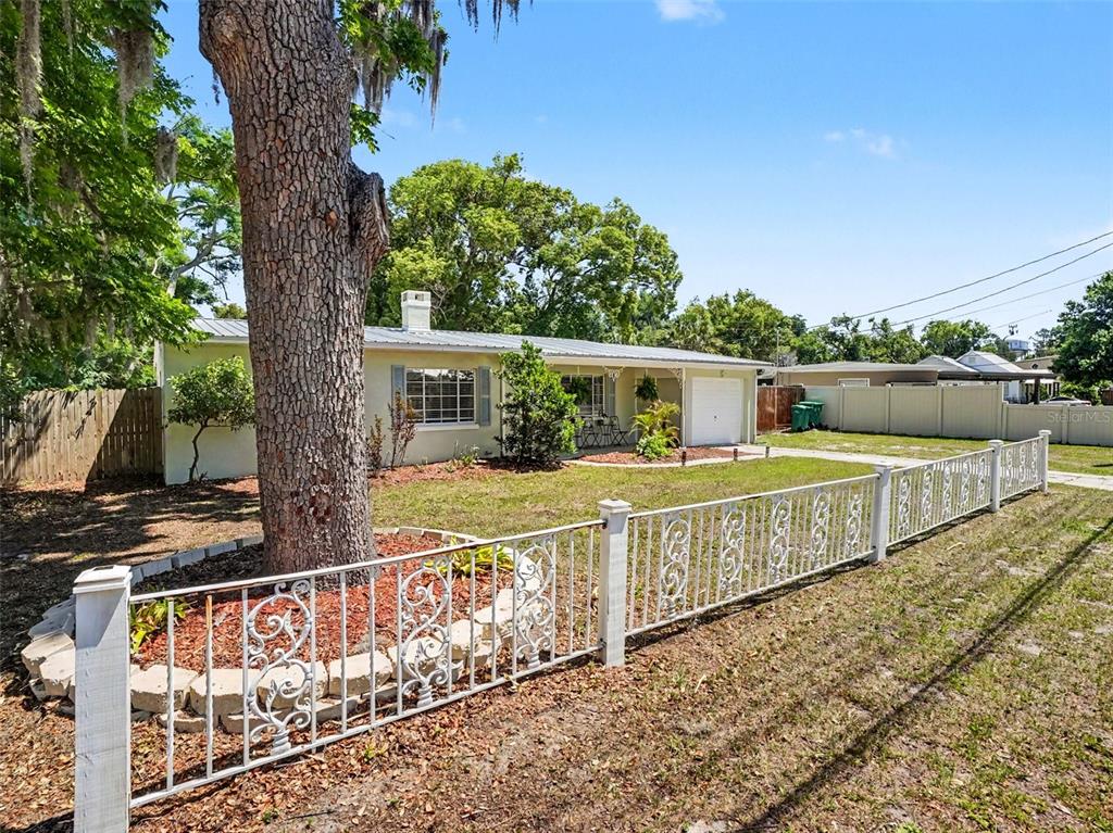 A single-story house with a white metal roof and a decorative metal front yard fence — 315 W 11TH AVENUE, MOUNT DORA, FL