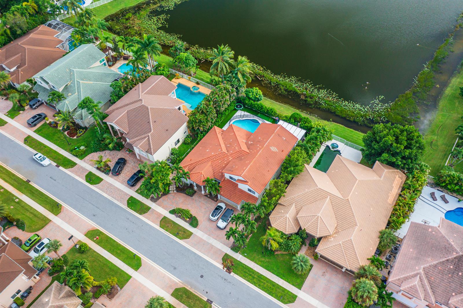 Aerial view of suburban houses with swimming pools and tiled roofs along a lake — 11804 Osprey Pointe Circle, Wellington FL 33449, WELLINGTON, FL