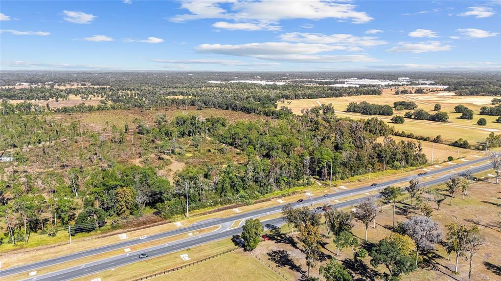 An aerial view shows a multi-lane highway running alongside a large, wooded, undeveloped plot of land — 1 PETITION UNIT 4261-1, OCALA, FL