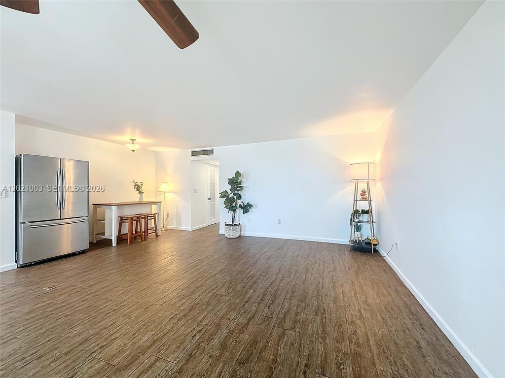 A spacious room features wood-look flooring, a stainless steel refrigerator, and a breakfast bar — 7133 Bay Dr # 705, Miami Beach FL 33141, MIAMI BEACH, FL