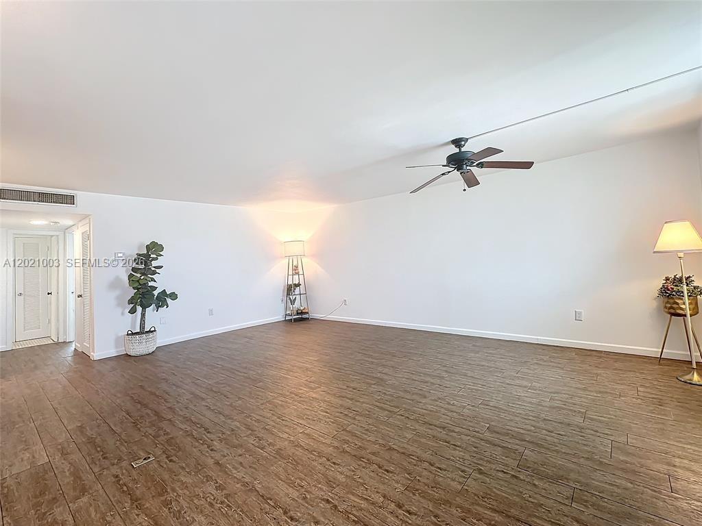 An empty room features wood-look tile flooring, white walls, a ceiling fan, and two lamps — 7133 Bay Dr # 705, Miami Beach FL 33141, MIAMI BEACH, FL