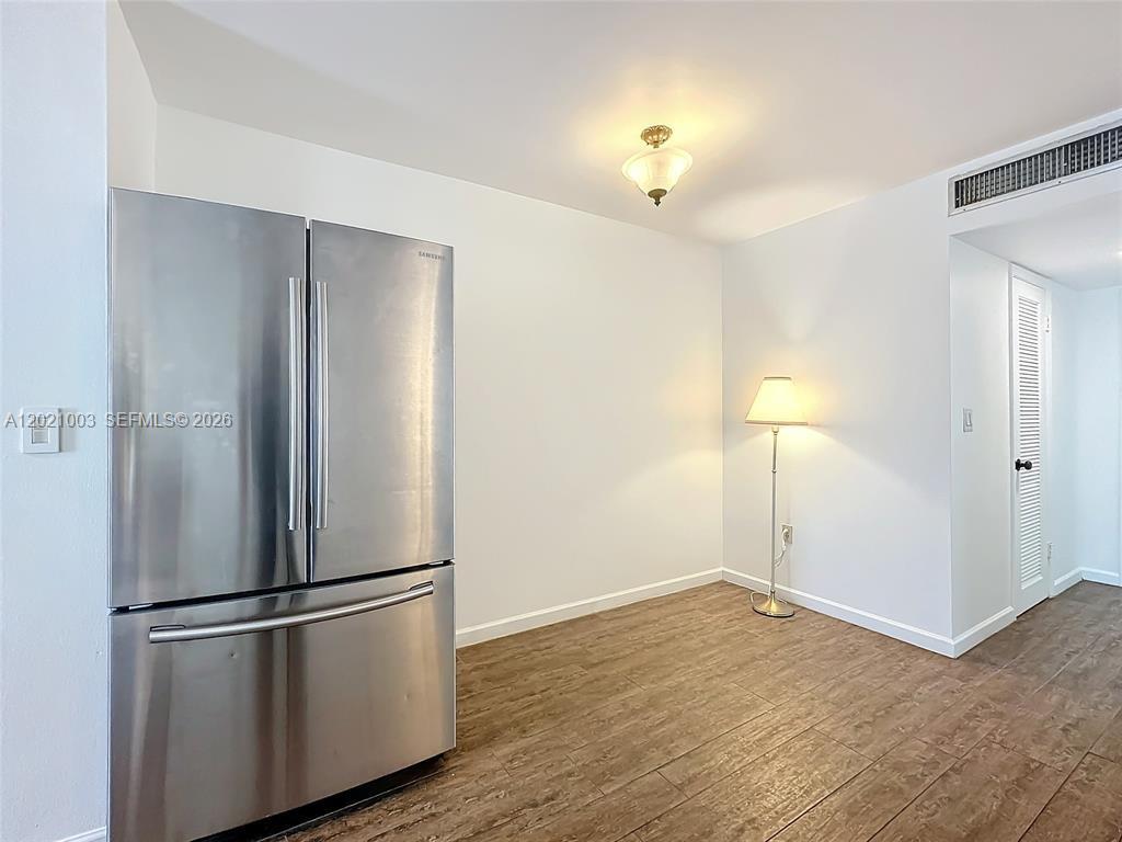 A stainless steel refrigerator stands in a room with white walls and wood-look flooring — 7133 Bay Dr # 705, Miami Beach FL 33141, MIAMI BEACH, FL