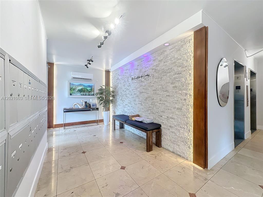 A building lobby features a stone accent wall, a wooden bench, and metal mailboxes — 7133 Bay Dr # 705, Miami Beach FL 33141, MIAMI BEACH, FL
