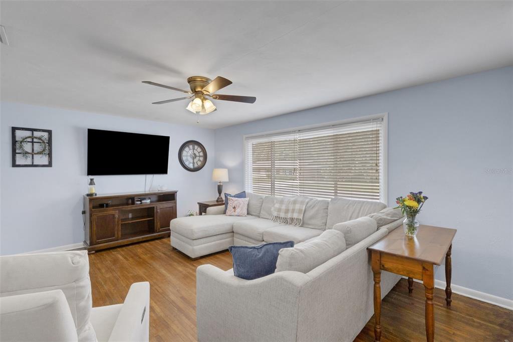A living room features a light-colored sectional sofa, a wooden media console, and hardwood floors — 2620 MARTIN AVENUE, LAKELAND, FL