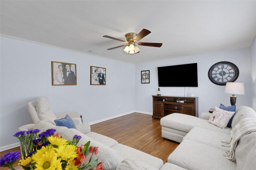 A living room features light blue walls, wood flooring, a ceiling fan, and sectional seating — 2620 MARTIN AVENUE, LAKELAND, FL