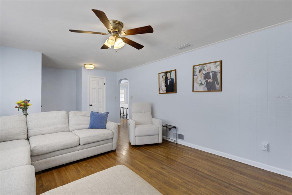 A living room features light blue walls, hardwood floors, a ceiling fan, and white furniture — 2620 MARTIN AVENUE, LAKELAND, FL