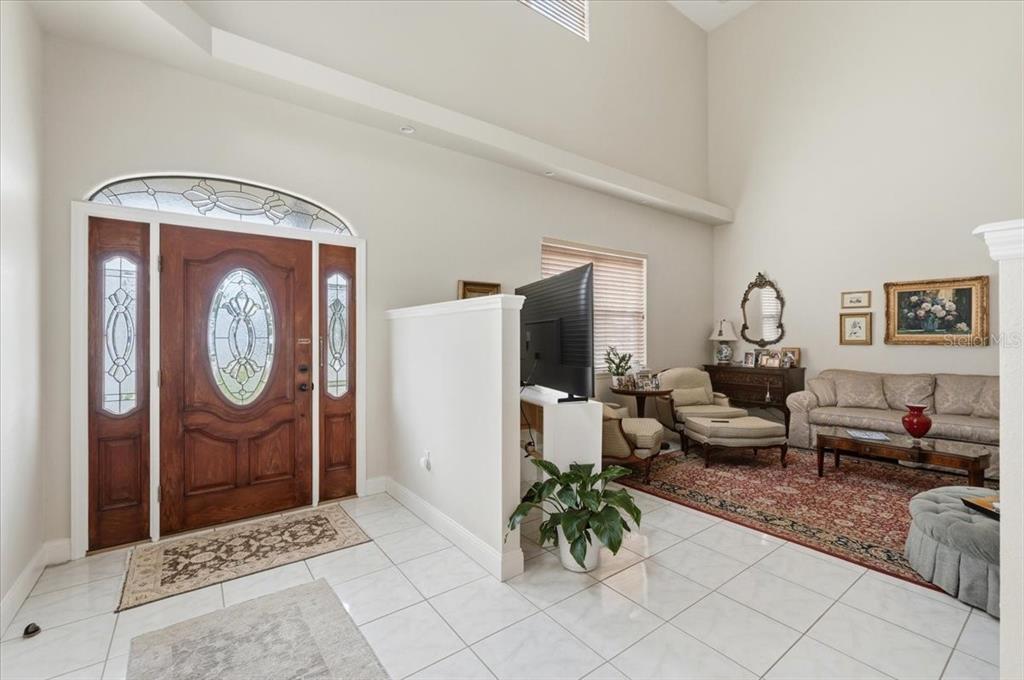 A bright entryway with tile floors leads into a living room with high ceilings — 1415 NEW JERSEY ROAD, LAKELAND, FL
