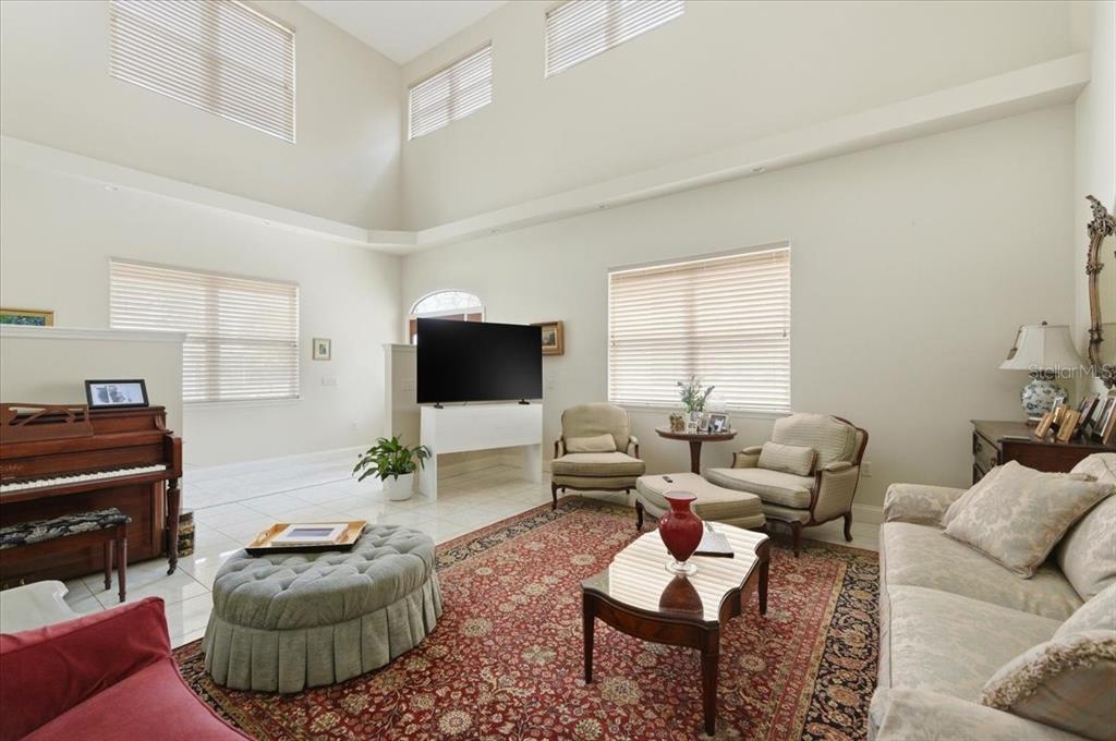 A spacious living room features high ceilings, a large area rug, and a piano — 1415 NEW JERSEY ROAD, LAKELAND, FL