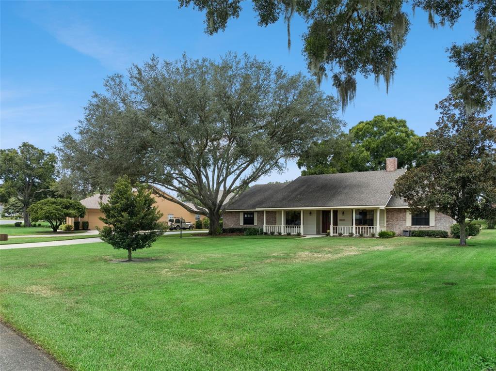 A single-story brick house with a front porch sits on a large, grassy lawn — 34035 PARK LANE, LEESBURG, FL