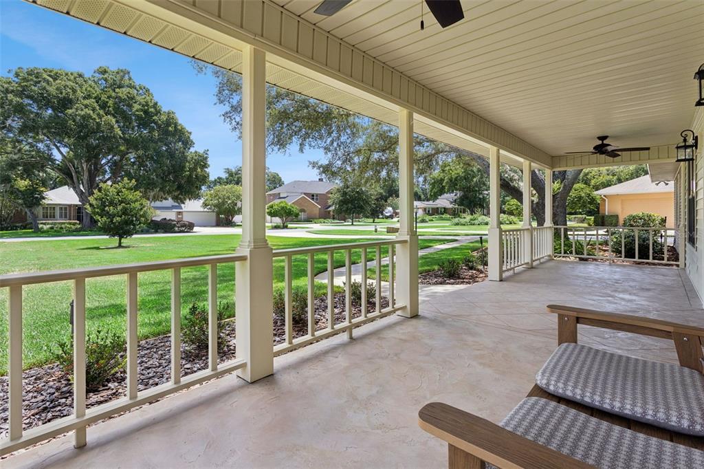 A covered porch features a concrete floor, white railings, and a view of a suburban neighborhood — 34035 PARK LANE, LEESBURG, FL