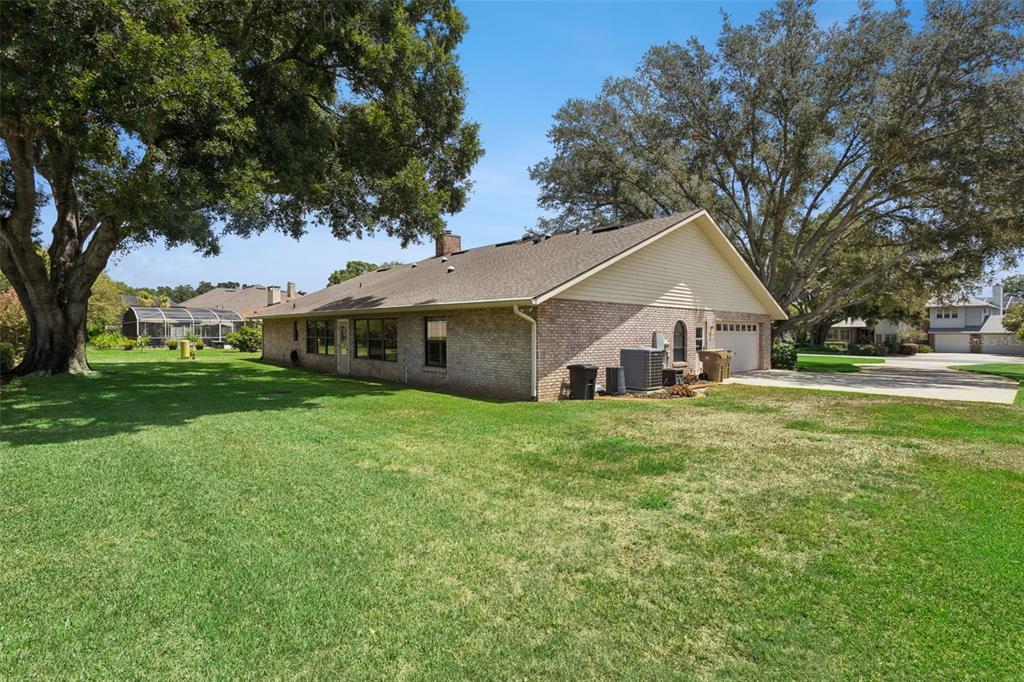A single-story brick house with a shingled roof sits on a large, grassy corner lot — 34035 PARK LANE, LEESBURG, FL