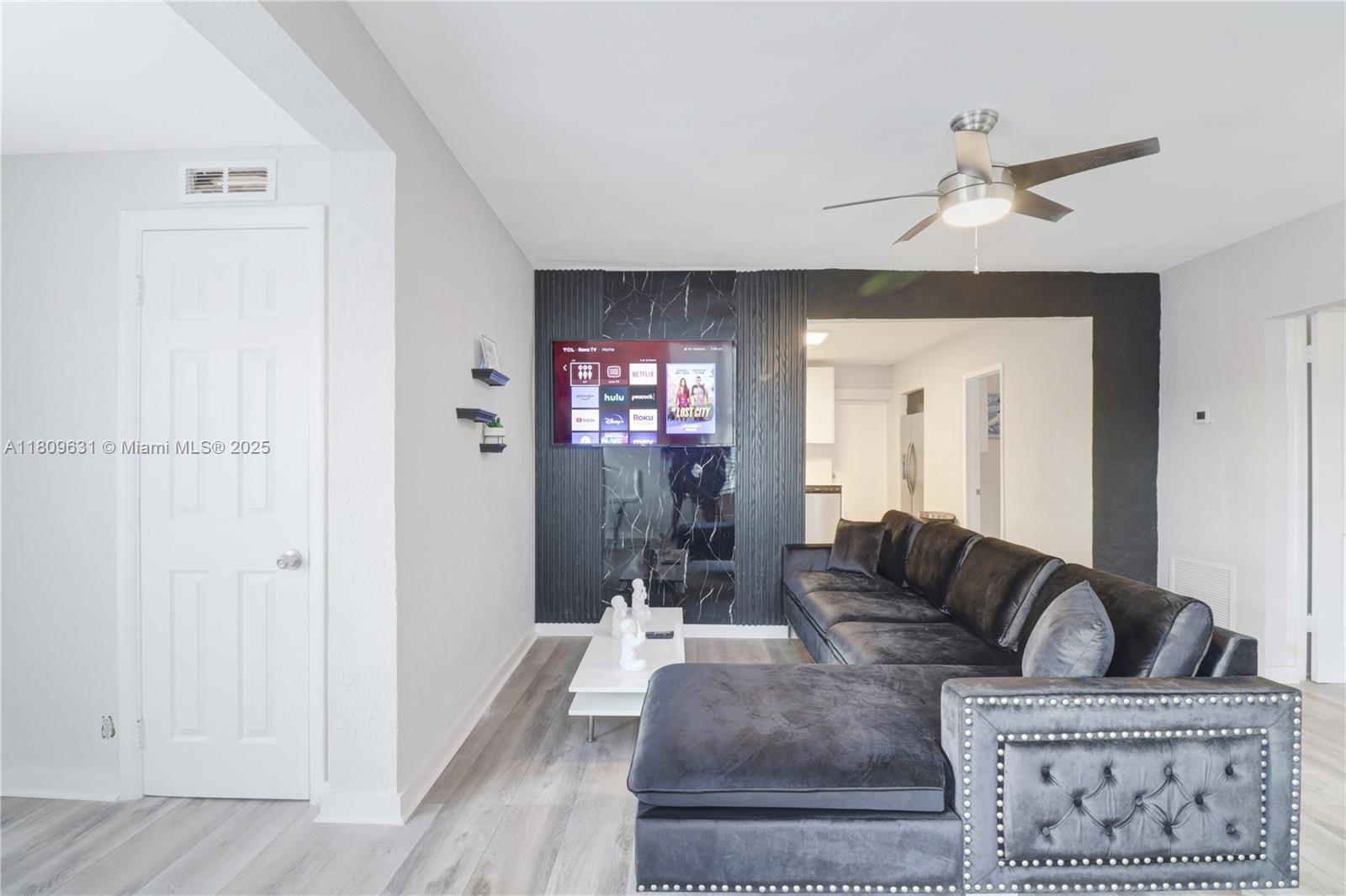 A living room features a black marble accent wall with a mounted television and sofa — 6039 SW 38th St, Miramar FL 33023, MIRAMAR, FL