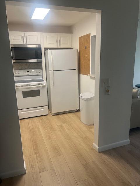 A kitchen with white appliances, light wood-look flooring, and white cabinetry — 90 Mansfield C, Boca Raton FL 33434, BOCA RATON, FL