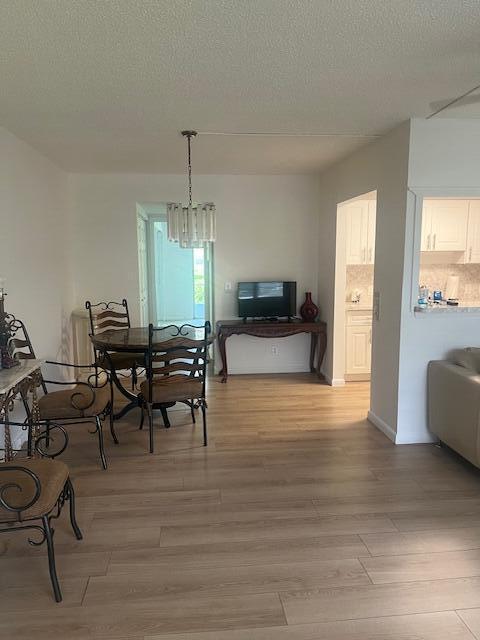 A dining area with a chandelier, table, and chairs sits next to a kitchen pass-through — 90 Mansfield C, Boca Raton FL 33434, BOCA RATON, FL