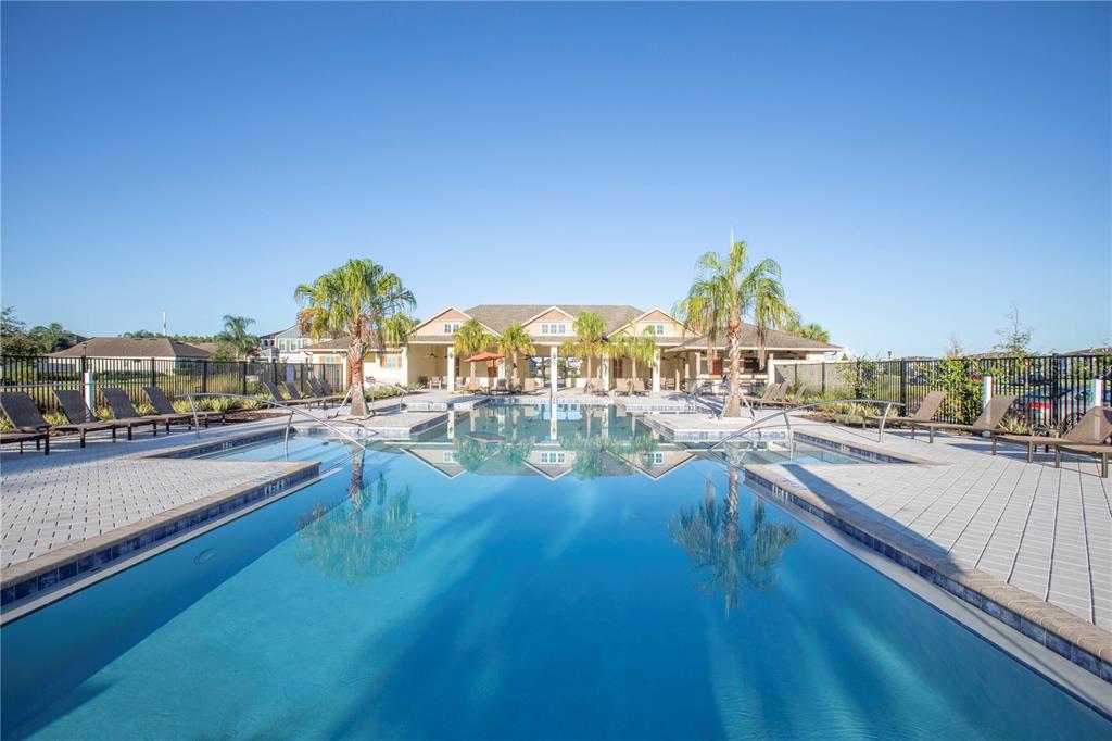 A swimming pool with lounge chairs and a clubhouse building under a clear blue sky — 8585 WINNING FIELDS ROAD, NEW PORT RICHEY, FL