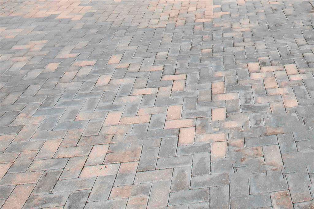 A close-up view of a driveway or patio paved with interlocking gray and tan bricks — 8585 WINNING FIELDS ROAD, NEW PORT RICHEY, FL