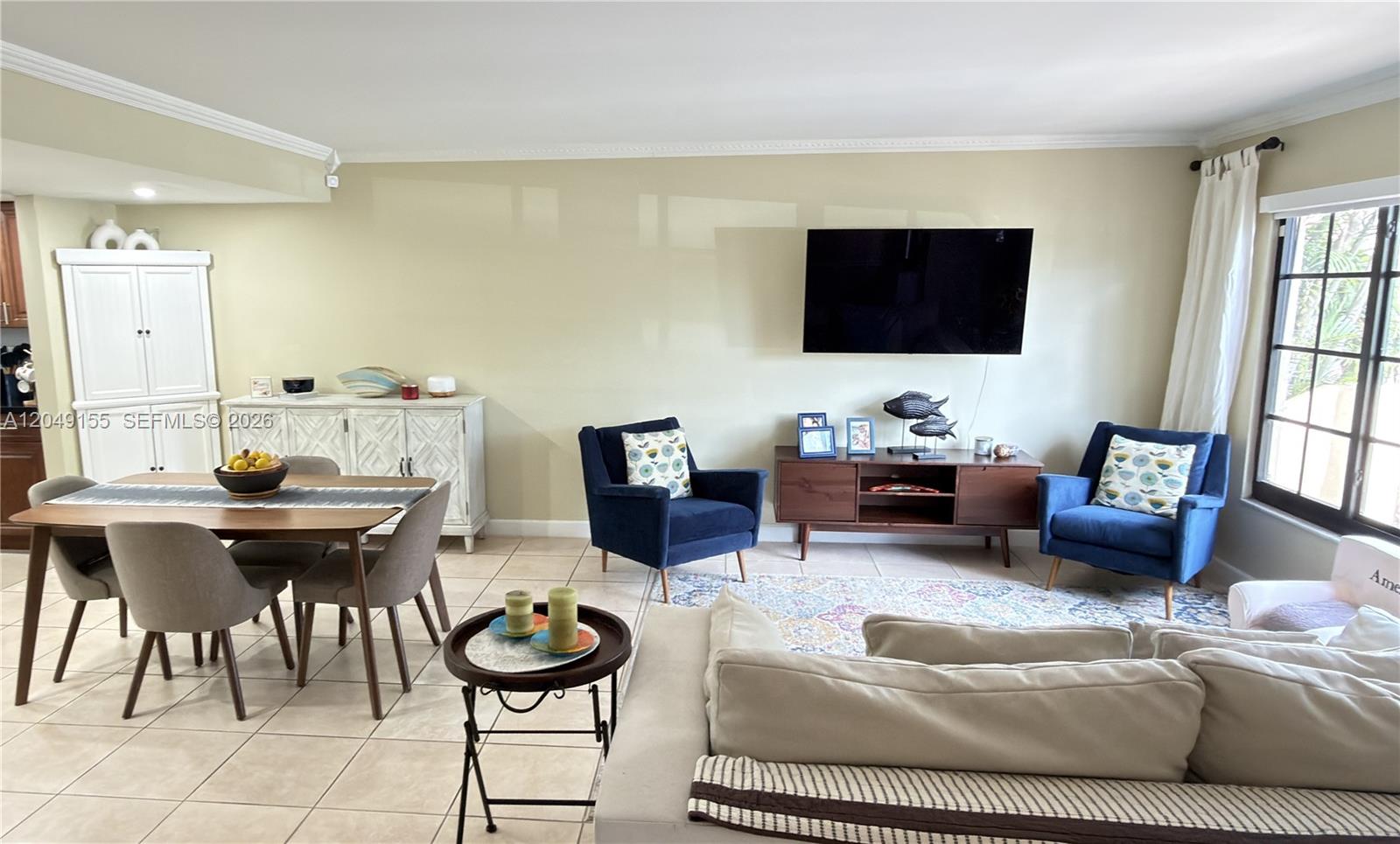 A living and dining area features tile floors, a wall-mounted television, and blue armchairs — 9492 NW 39th St, Sunrise FL 33351, SUNRISE, FL