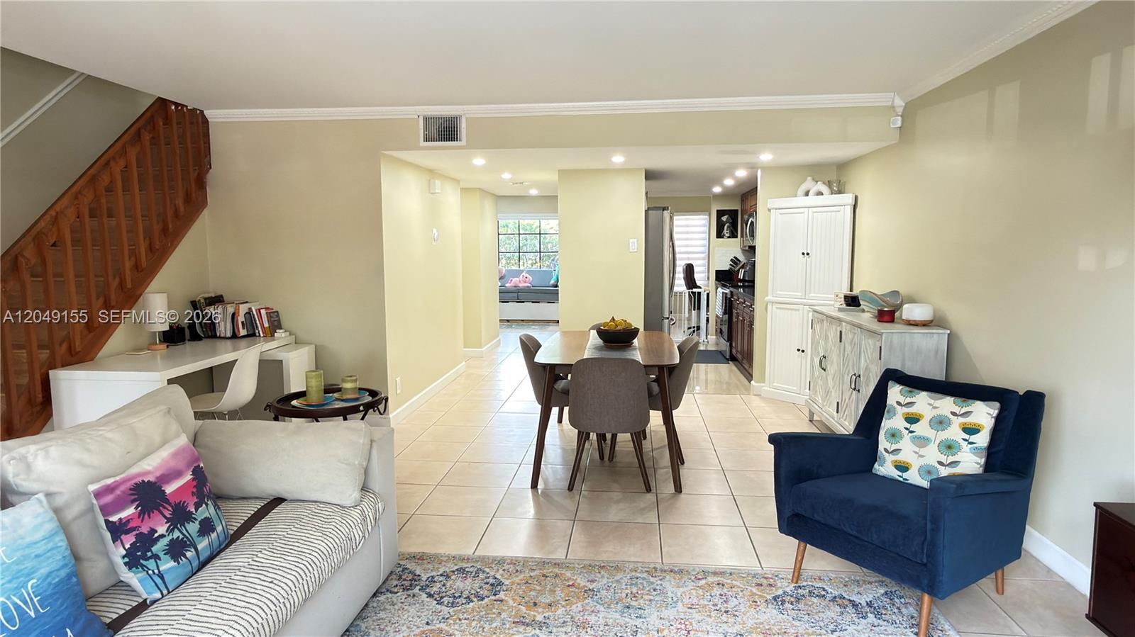 This open-concept living and dining area features tile flooring, a wooden staircase, and neutral walls — 9492 NW 39th St, Sunrise FL 33351, SUNRISE, FL