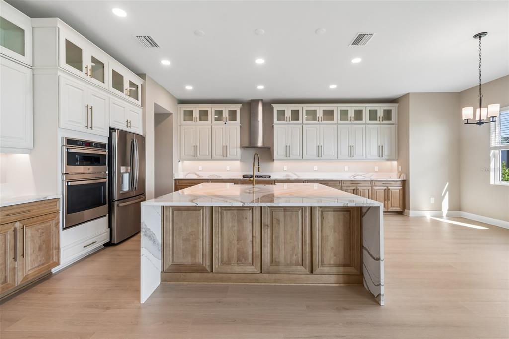 A kitchen features a large marble-topped island, two-tone cabinetry, and stainless steel appliances — 1170 KINGS WAY DRIVE, NOKOMIS, FL