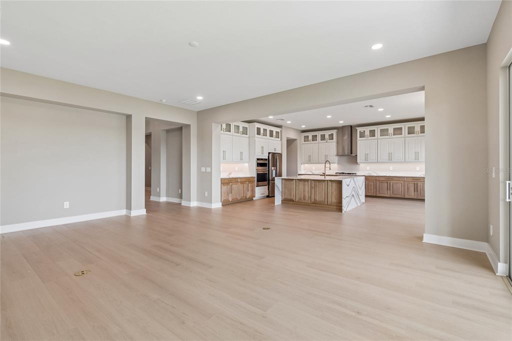 A spacious open-concept kitchen features two-toned cabinetry, a large marble-topped island, and light wood flooring — 1170 KINGS WAY DRIVE, NOKOMIS, FL