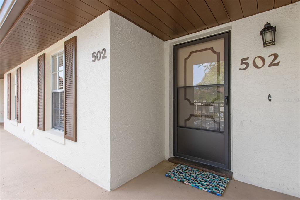 The exterior entrance features a white stucco wall, a dark storm door, and brown shutters — 600 NORTHERN WAY UNIT 502, WINTER SPRINGS, FL