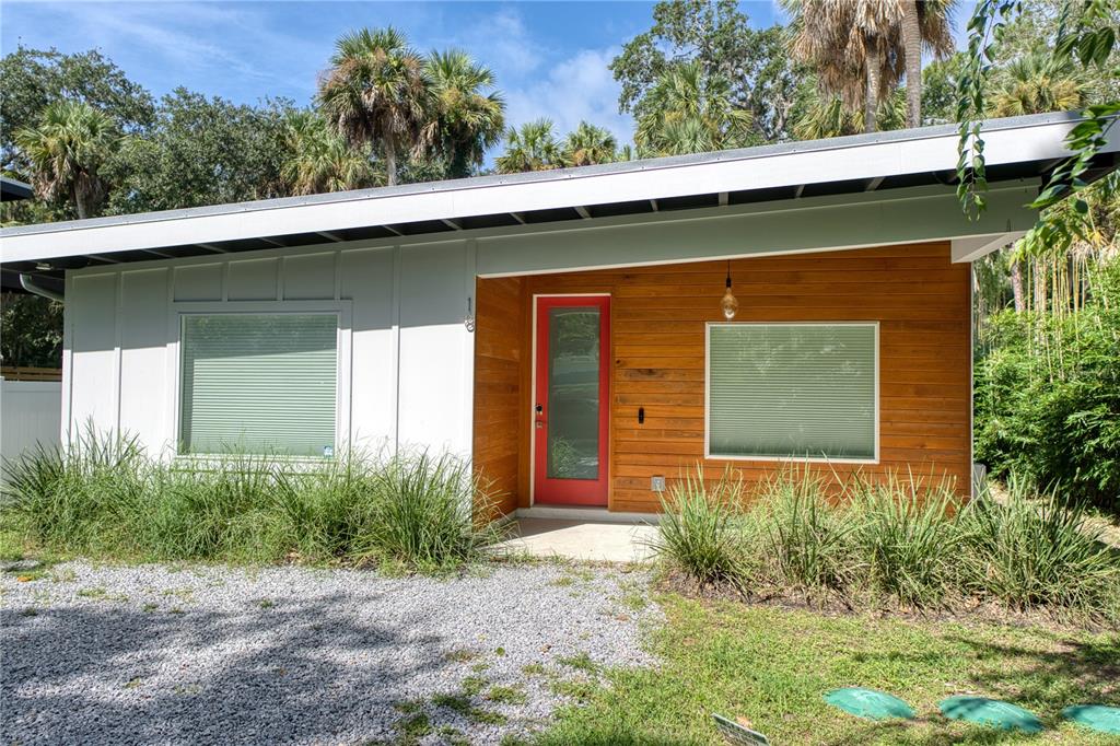 A modern one-story house features white siding, wood paneling, and a bright red front door — 18 SANCHEZ AVENUE, PALM COAST, FL