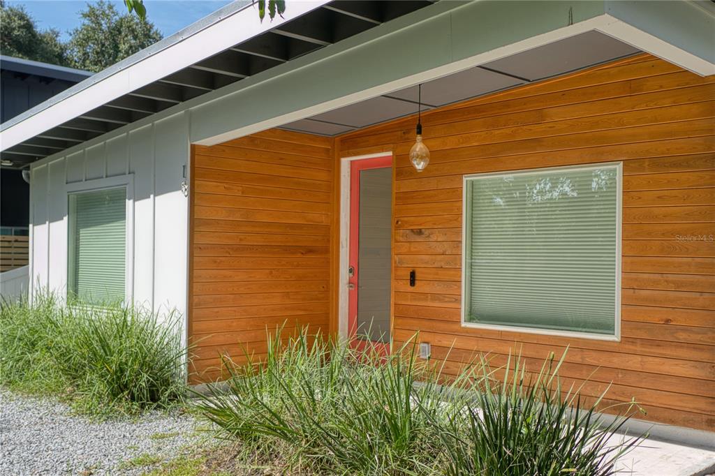 A modern home exterior features horizontal wood siding, a red front door, and white walls — 18 SANCHEZ AVENUE, PALM COAST, FL