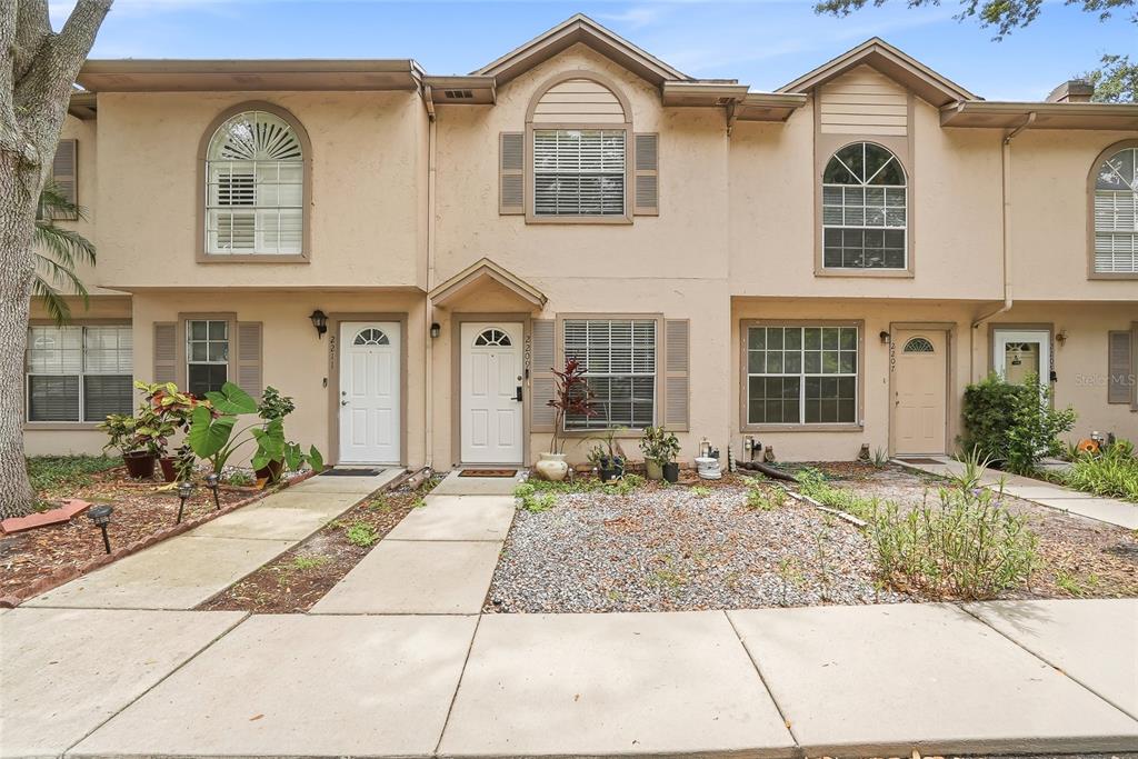 A row of three beige townhouses with arched windows and concrete walkways in front — 2209 FLETCHERS POINT CIRCLE, TAMPA, FL