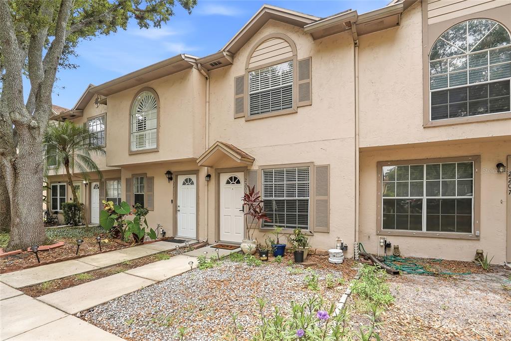 The exterior of a two-story townhouse complex with tan stucco walls and white front doors — 2209 FLETCHERS POINT CIRCLE, TAMPA, FL