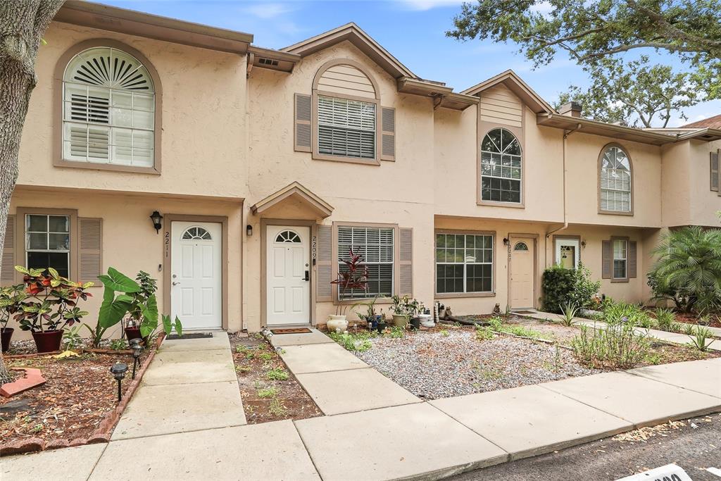 A row of two-story townhomes with beige stucco siding, arched windows, and concrete walkways — 2209 FLETCHERS POINT CIRCLE, TAMPA, FL