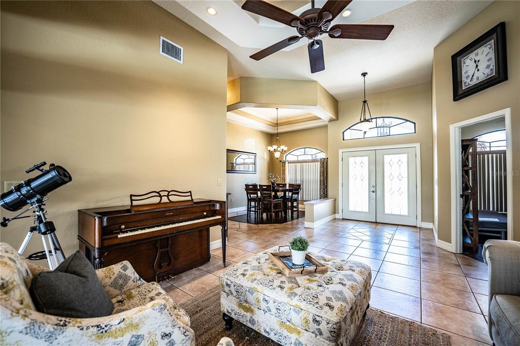 A living room features a piano, a telescope, a patterned ottoman, and a dining area — 2205 CHESTERFIELD CIRCLE, LAKELAND, FL