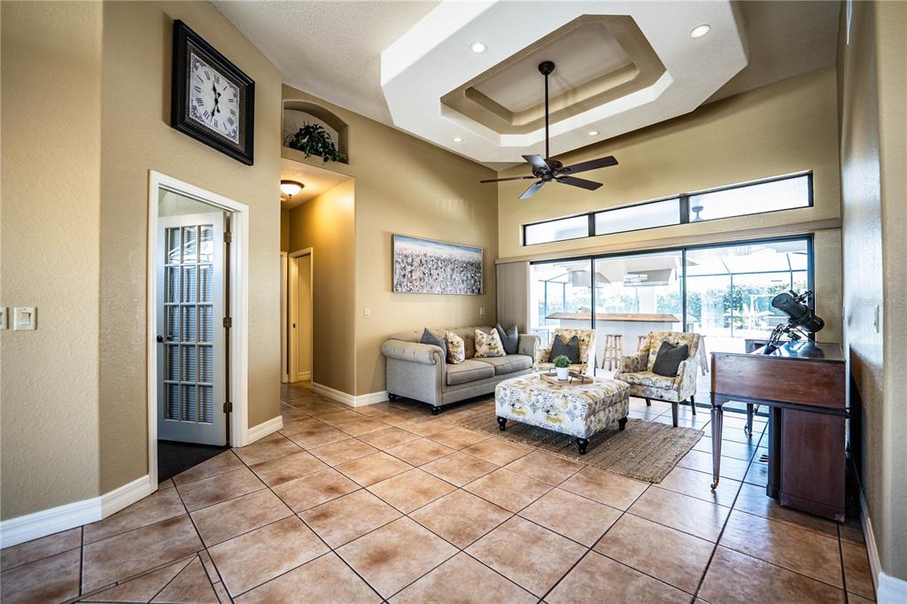 A living room with tile floors, a tray ceiling, and a view of a pool — 2205 CHESTERFIELD CIRCLE, LAKELAND, FL