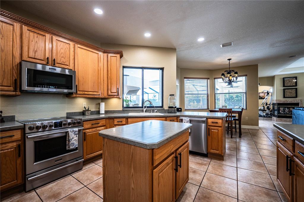 A kitchen with oak cabinets, stainless steel appliances, a center island, and tile flooring — 2205 CHESTERFIELD CIRCLE, LAKELAND, FL