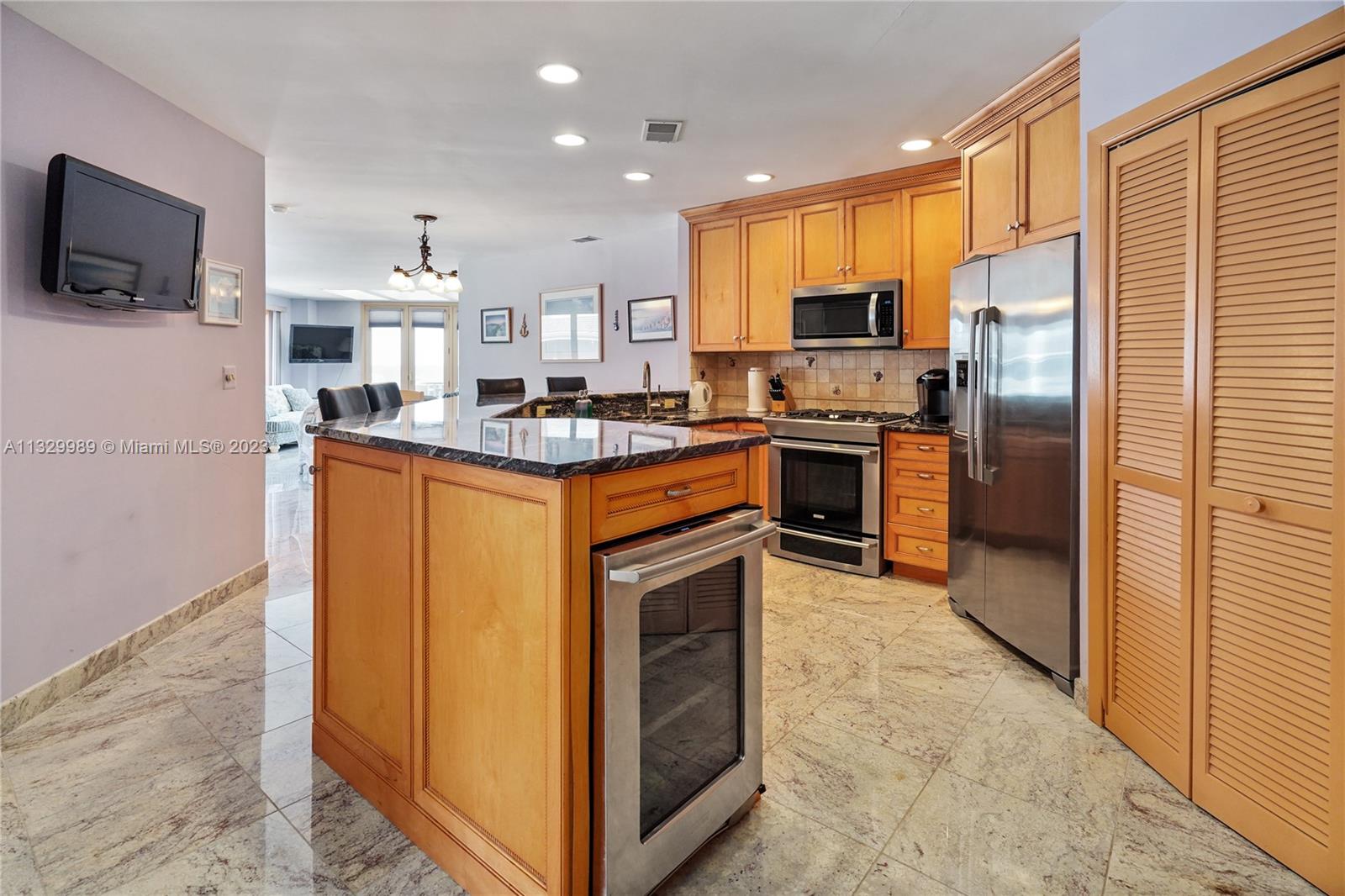 A kitchen features light wood cabinets, stainless steel appliances, a granite island, and tiled floors — 900 Ocean Ave # 108, NJ 08742, NJ