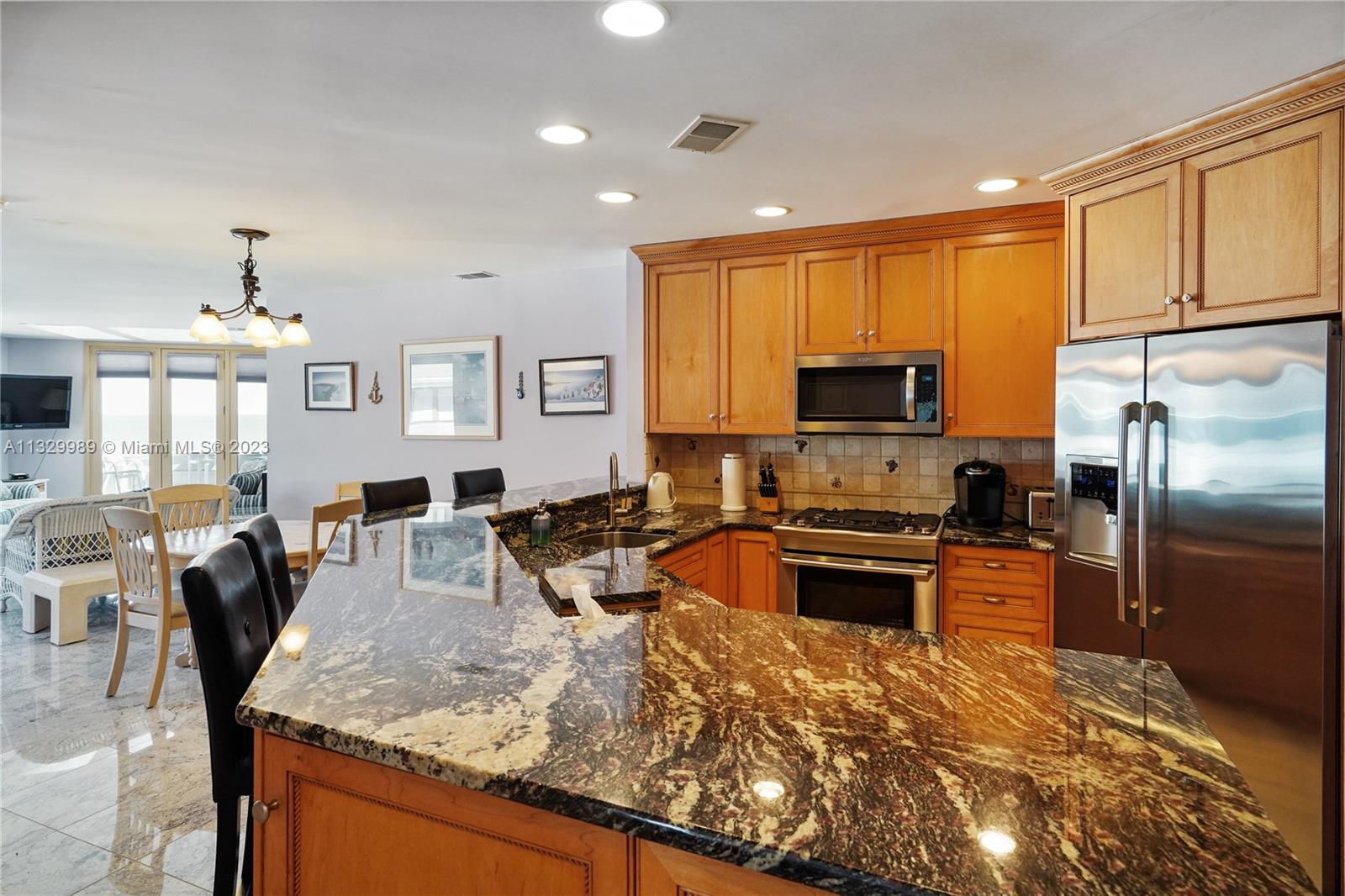 A kitchen features wood cabinets, dark granite countertops, stainless steel appliances, and a breakfast bar — 900 Ocean Ave # 108, NJ 08742, NJ