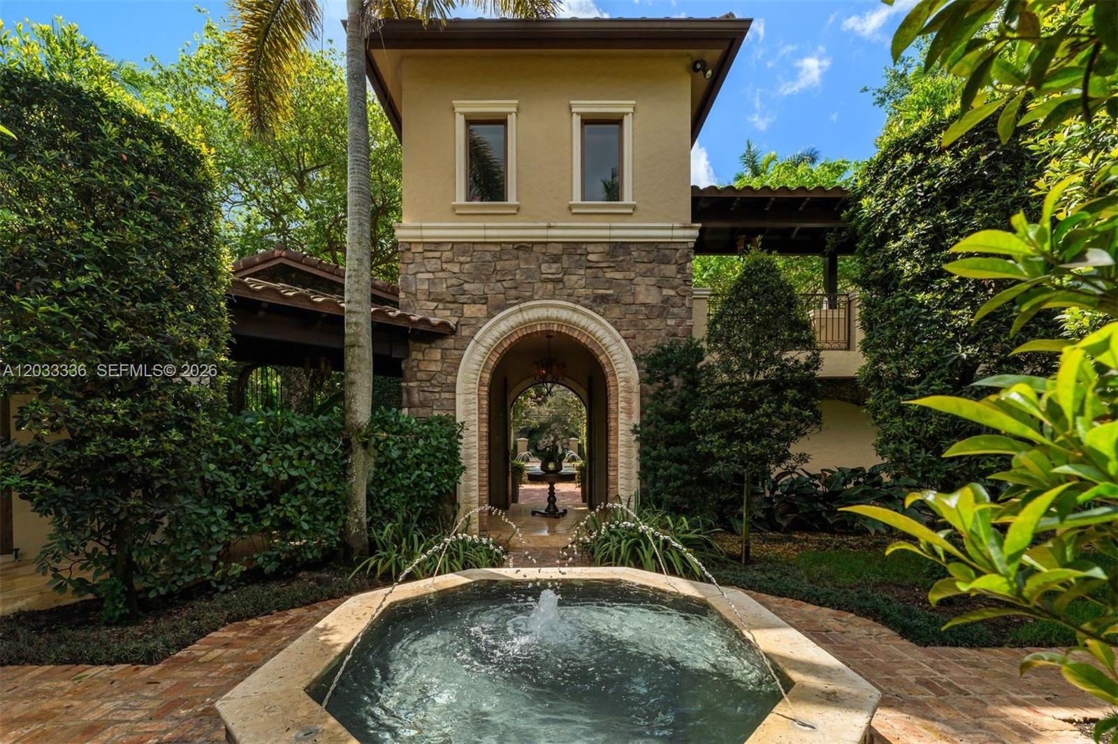 A stone tower with an arched entryway stands behind a stone fountain in a garden — 6201 SW 96th St # 0, Pinecrest FL 33156, PINECREST, FL