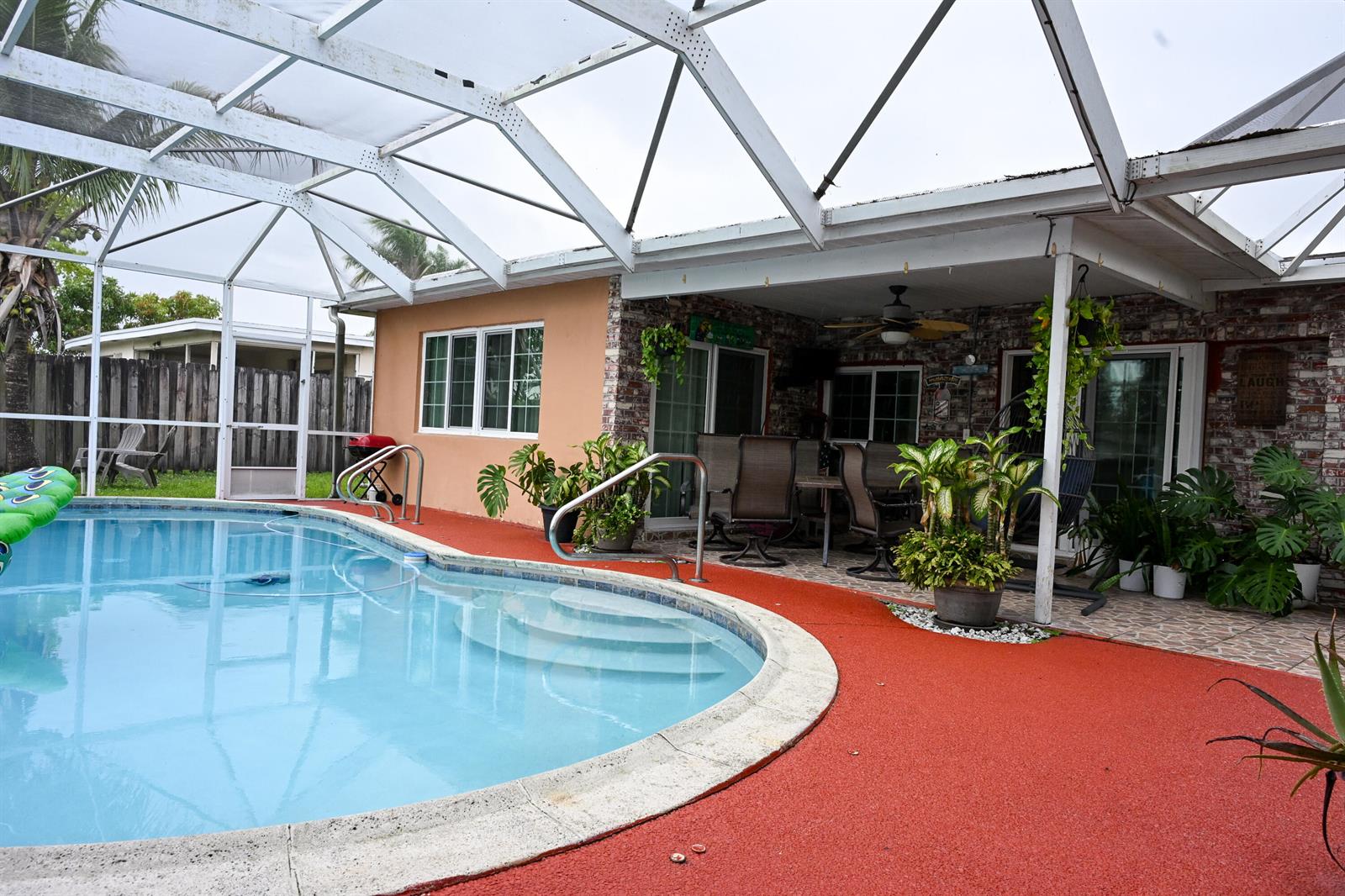 A swimming pool with a red deck sits under a screened-in patio enclosure — 8610 NW 27th Place, Sunrise FL 33322, SUNRISE, FL