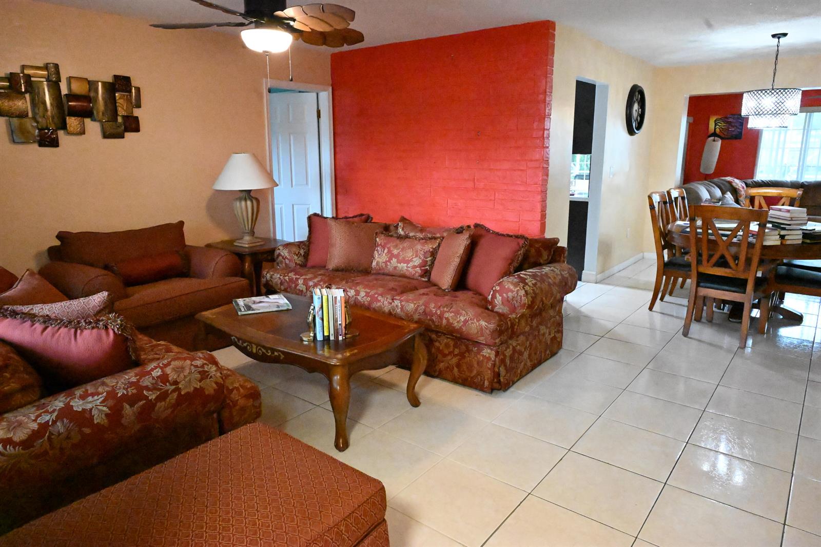 A living room with a red brick wall, tiled floors, and traditional patterned furniture — 8610 NW 27th Place, Sunrise FL 33322, SUNRISE, FL