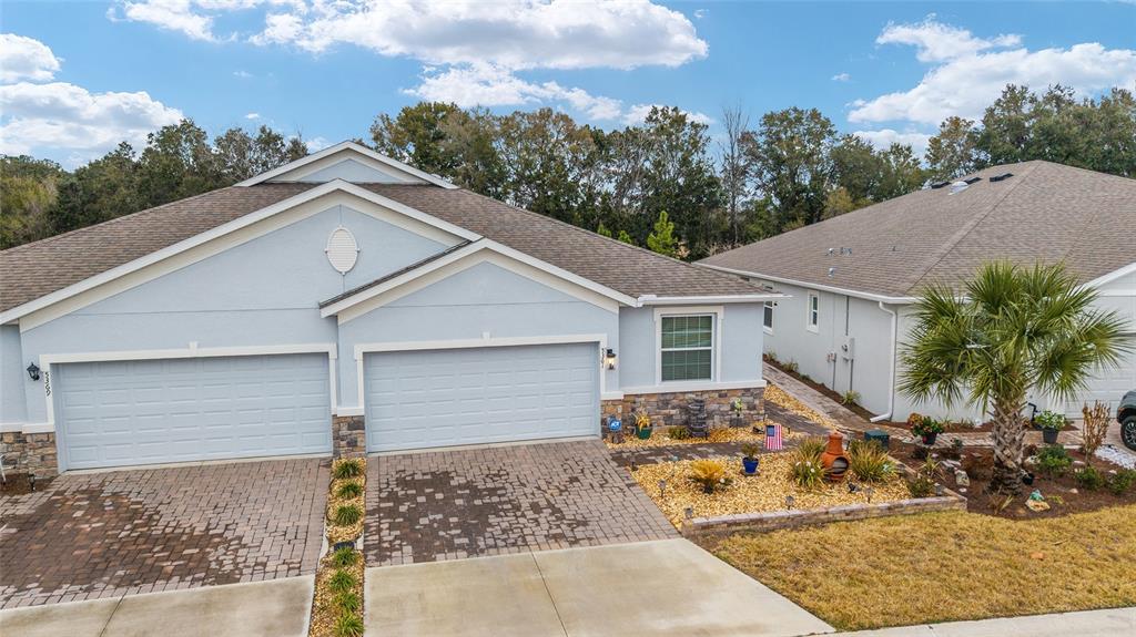 A light blue duplex with two garage doors, stone accents, and a paved driveway — 5361 NW 48TH PLACE, OCALA, FL