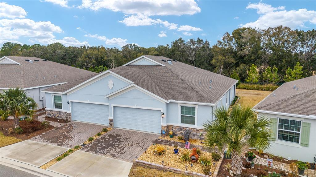 An exterior view of a light blue duplex home with a stone facade and paved driveways — 5361 NW 48TH PLACE, OCALA, FL