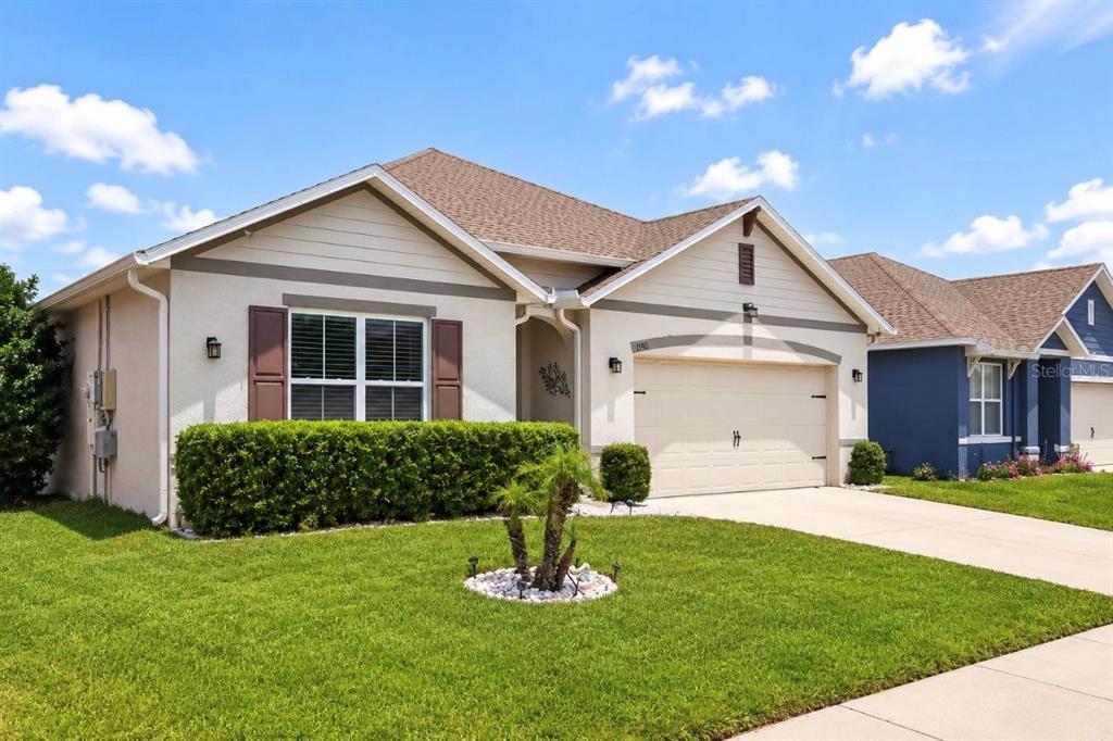 A single-story house with a beige stucco exterior, brown shutters, and a two-car garage — 3155 COUNTRY CLUB CIRCLE, WINTER HAVEN, FL