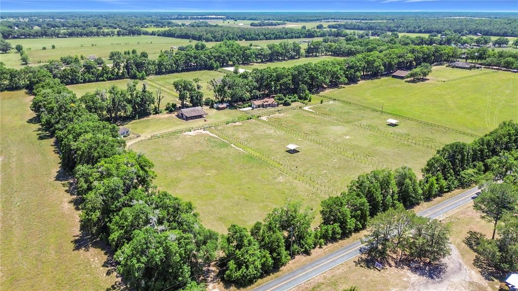 An aerial view shows a rural property with a house, barns, and fenced pastures — 20540 SW 5TH PLACE, DUNNELLON, FL