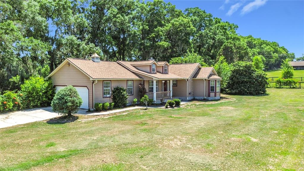 A single-story tan house with a brown roof sits on a large grassy lot — 20540 SW 5TH PLACE, DUNNELLON, FL