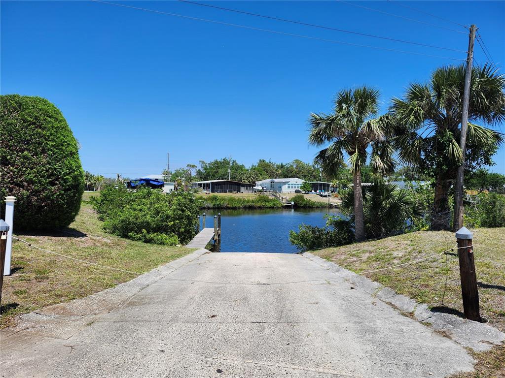 A concrete boat ramp leads down to a small canal with a wooden dock — 1252 KINGFISHER DRIVE, ENGLEWOOD, FL