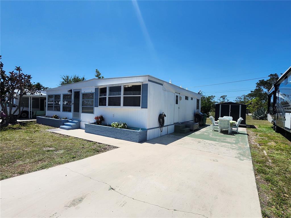 A single-story mobile home with a blue painted driveway and a small storage shed — 1252 KINGFISHER DRIVE, ENGLEWOOD, FL