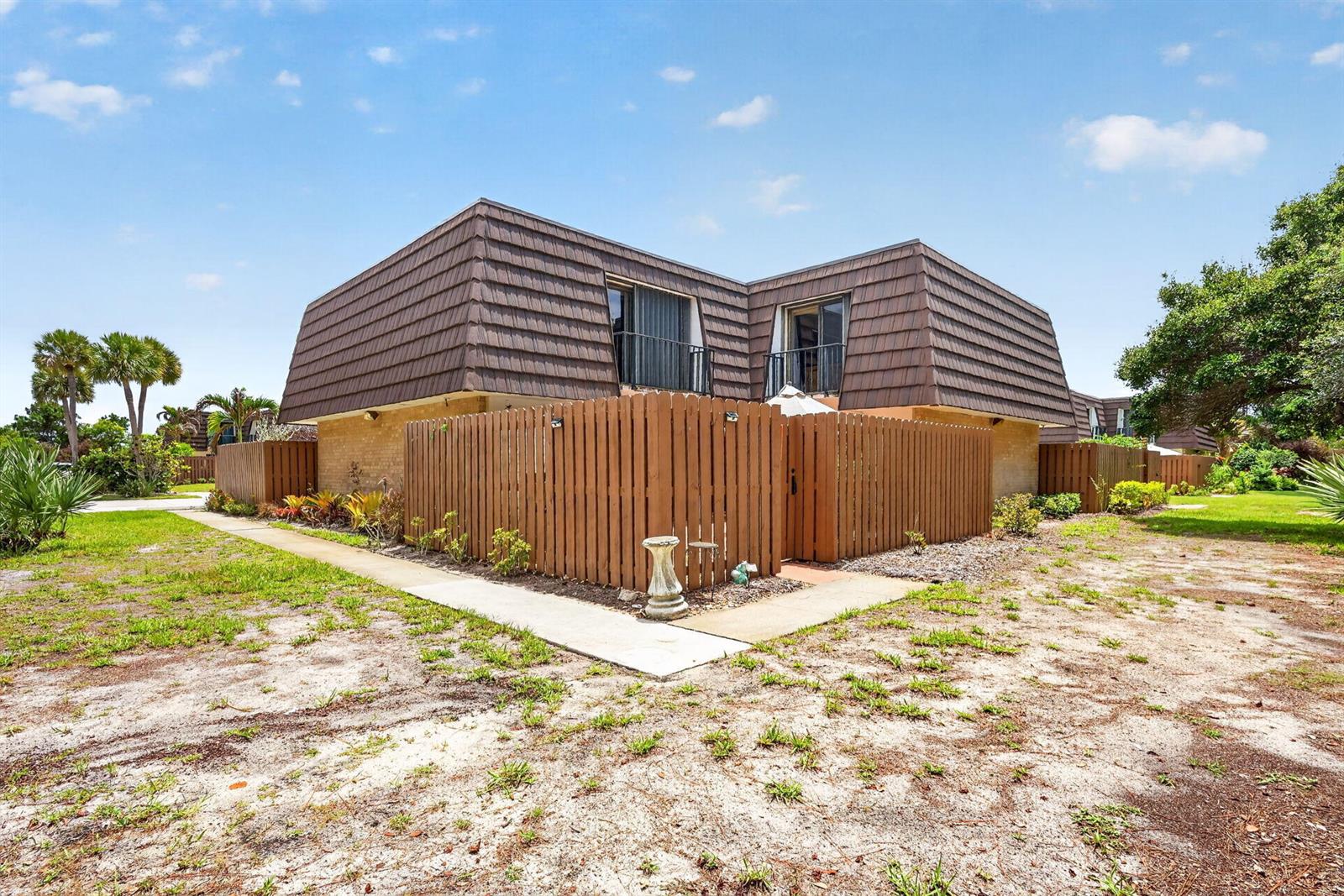 A two-story building with a mansard roof and a wooden privacy fence in the foreground — 5706 SE Riverboat Drive # 202, Stuart FL 34997, STUART, FL