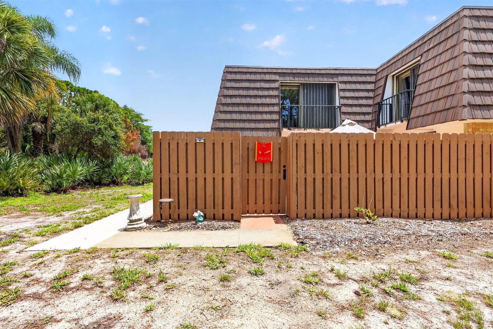 A wooden privacy fence encloses a patio area in front of a two-story townhome — 5706 SE Riverboat Drive # 202, Stuart FL 34997, STUART, FL