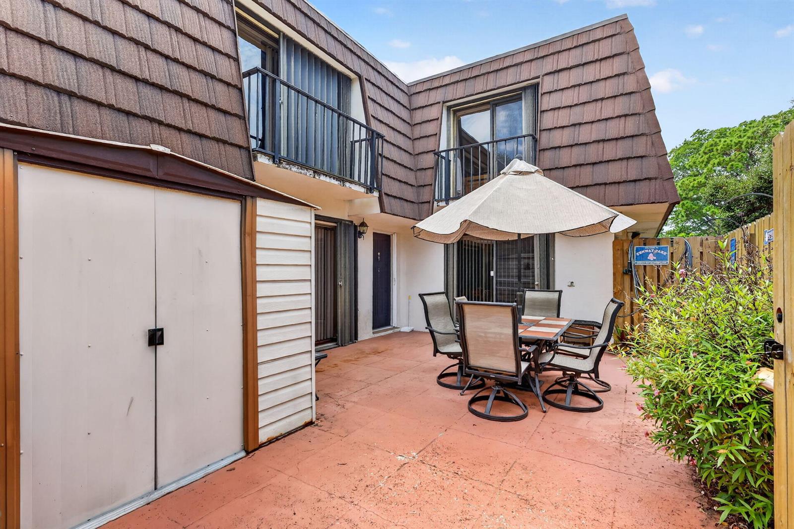 A patio with a dining set and umbrella sits outside a two-story residential building — 5706 SE Riverboat Drive # 202, Stuart FL 34997, STUART, FL