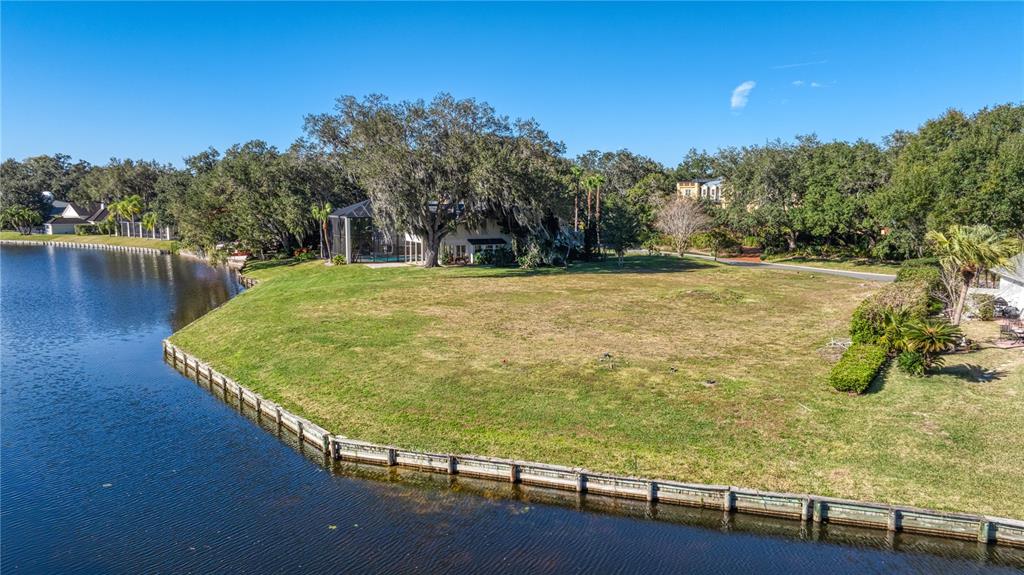 An aerial view of a grassy waterfront lot with a bulkhead and a nearby house — 814 TARAY DE AVILA, TAMPA, FL
